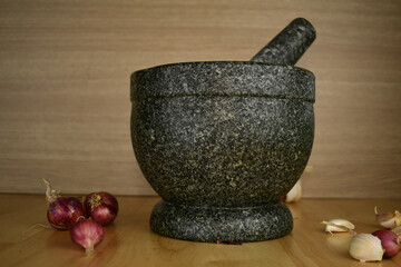garlic and red onions on a wooden with black stone 
mortar background