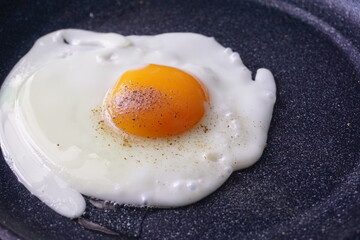 Fried eggs on the pan and peppered on top