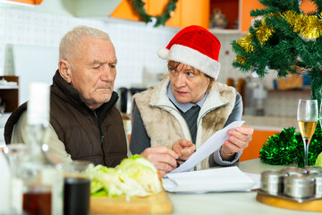 Image of aged family trying to pay utility bills before new year dinner