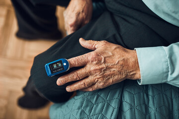 Senior man measuring the degree of oxygen saturation of the blood and heart rate at home using...