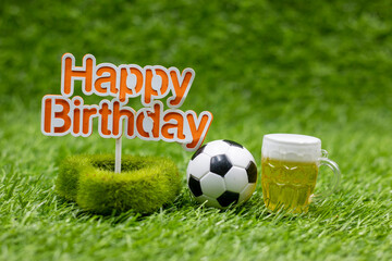 Soccer birthday with golf ball and beer and happy birthday sign are on green grass