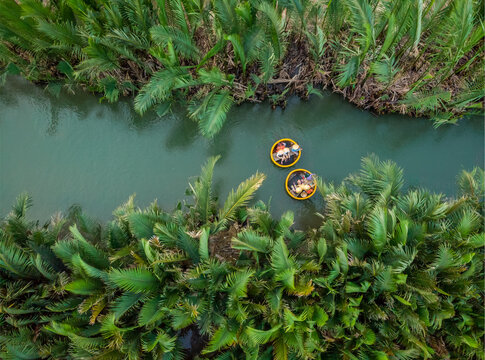 Hội An, Vietnam - 29 April 2019: Aerial view of tourists doing an excursion on board of small circular coconut boats in Thu Bon river.