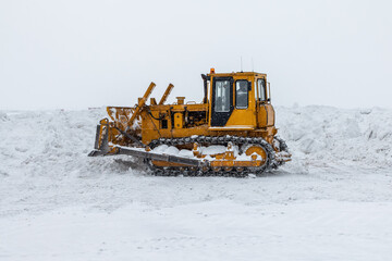 Yellow bulldozer removes snowdrifts in a severe blizzard at winter © Dushlik