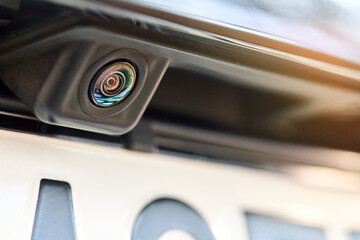 Obraz na płótnie Canvas Luxury car rear view camera for parking assistance selective focus close up with sunflare and copyspace. Concept of safety car driving while parking process. Assist device equipment in modern cars.