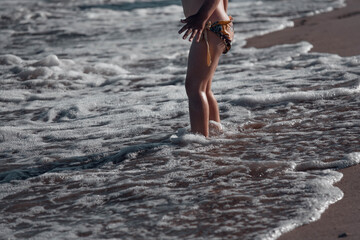 A child on the beach. Children's feet on the background of the contrasting sun are immersed in the...
