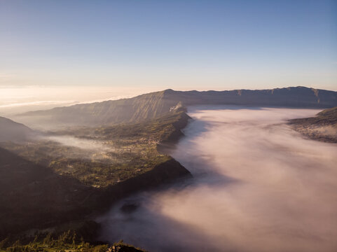 Aerial view of Mount Bromo north ridge with clouds covering the valley at sunrise, an active volcano in East Java, Indonesia.