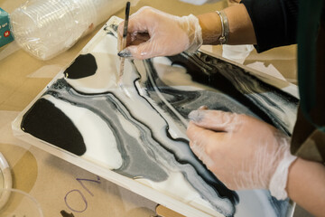 Fototapeta premium at the workshop on creating fluid art hands in gloves distribute black and white resin on resin art picture