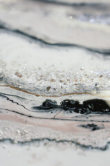 vertical background modern abstract design made with epoxy resin. splashes of silver stones on a milky background with black veins