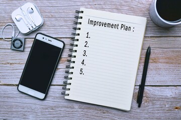 Improvement plan text on wooden desk with accessories