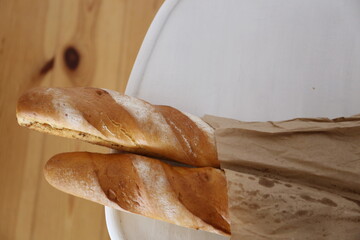 two French baguettes in a paper bag on the table