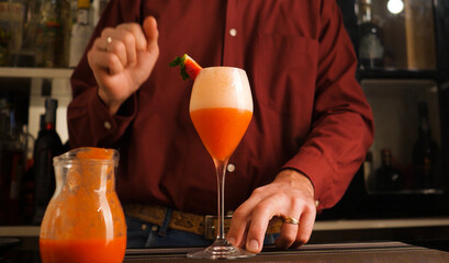 Barman prepares an Italian cocktail called Fragolino with strawberry juice and sparkling wine.