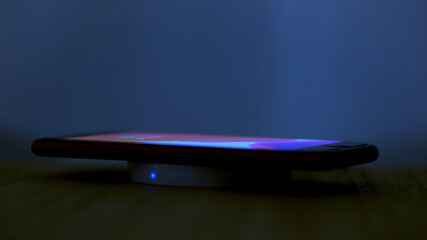 Wireless induction charger base for mobile phone. Moonlight scene while a smartphone is placed on...