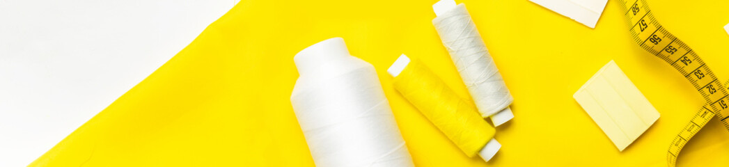 Tailoring concept. beautiful yellow fabric with sewing thread and tape measure, scissors . Top view. Flat lay. banner