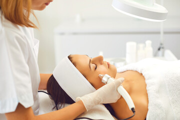 Cosmetologist making procedure of ultrasound Microdermabrasion for young woman
