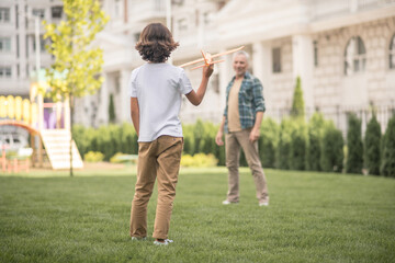 Dad and son playing together on a lawn and looking involved