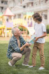 Gray-haired man giving a gift box to his son