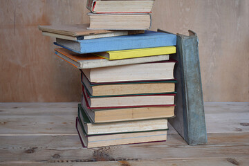 A stack of old books on a wooden shelf.