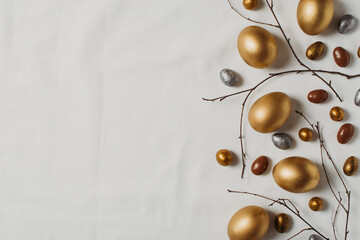 Easter concept with golden eggs and twigs flat lay on white texture background