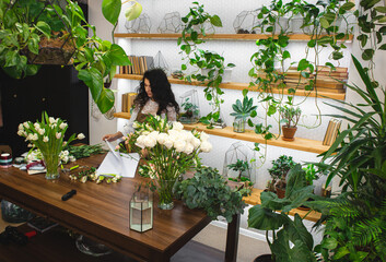 Attractive young woman florist is working in a flower shop