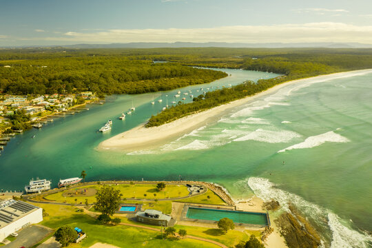 Aerial view of a small boats fleet sailing the Currambene creek at sunset, Huskisson, New South Wales, Australia.