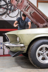 Young caucasian male is seen wrenching an engine or engine bay of an old vintage car. Tune up or...