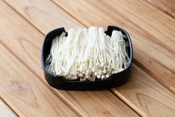 fresh raw mushroom sliced on square plate isolated on wooden background, shabu, hot pot ingredients