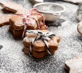 Star shaped baked gingerbread cookies sprinkled with powdered sugar on a black table