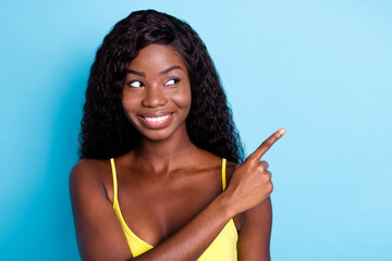 Portrait of lovely confident cheerful wavy-haired girl pointing forefinger copy space ad isolated over pastel blue color background