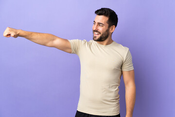 Young handsome man with beard over isolated background giving a thumbs up gesture