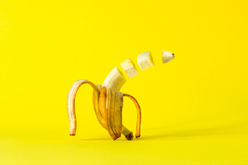 Creative idea of a banana with slices in the air on a bright yellow background. Food levitation...