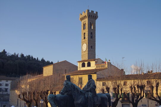 Monument of the meeting of Teano between Giuseppe Garibaldi and Vittorio Emanuele II and bell tower of the cathedral in Mino da Fiesole square, Tuscany, Italy