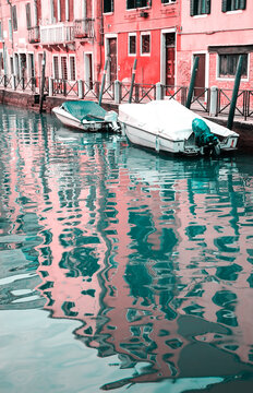 Venetian Carnival dream. Canal in Venice. Boats and reflection of houses in the water. Retro toned photo.