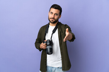 Photographer man over isolated purple background shaking hands for closing a good deal