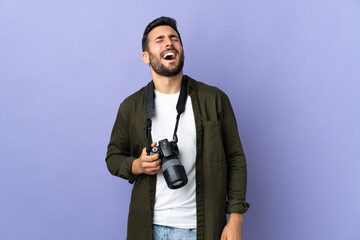 Photographer man over isolated purple background laughing