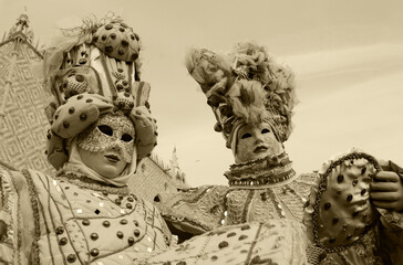 Two noble masks with Doge's Palace at background. St Mark's Square during traditional Carnival in...