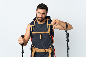 Young mountaineer man with a big backpack and trekking poles isolated on white background showing...