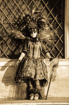 Peacock mask in sunlight near Doge's Palace in St Mark's Square at traditional Carnival in Venice, Italy. Sepai historic photo