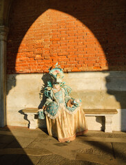 A mask in sunlight near Doge's Palace in St Mark's Square during traditional Carnival in Venice, Iitaly