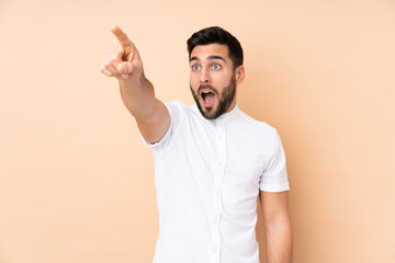 Caucasian handsome man isolated on beige background pointing away