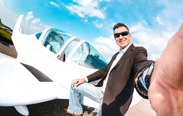 Young confident man taking selfie with mobile smart phone at private airplane - Modern business...