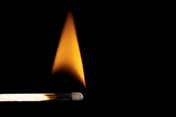 Close-up of a burning matchstick against a black background.