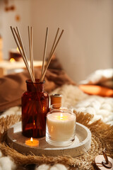 Air reed freshener and burning candles on bed indoors. Interior elements