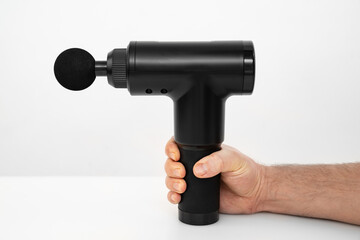 men's hands holds massage gun. medical-sports device helps to reduce muscle pain after training, helps to relieve fatigue, affects problem areas of body, improves condition of skin.