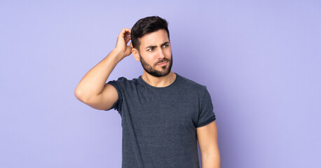 Caucasian handsome man having doubts while scratching head over isolated purple background