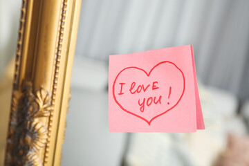 Note with phrase I Love You attached to mirror