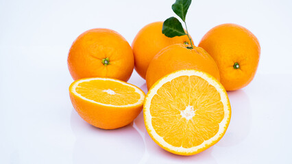 Cut in half and slice a ripe orange with golden yellow peel. Lots on white background with shadows and reflections