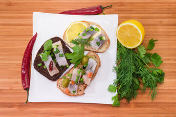 Different open sandwiches with pickled herring on dish, top view
