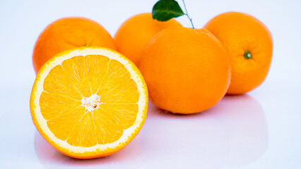 Cut in half and slice a ripe orange with golden yellow peel. Lots on white background with shadows and reflections