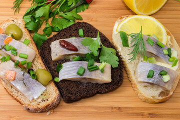 Open sandwiches with pickled herring on cutting board close-up