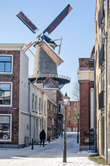 Schiedam, The Nethelrands, February 11, 2021: view trhough an alley in the historic center towards De Walvisch (The Whale), one of the town's large windmills